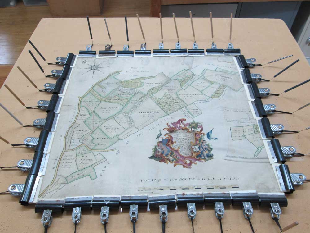 A humidified map on parchment being dried under slight tension to encouraged it to lay flat.